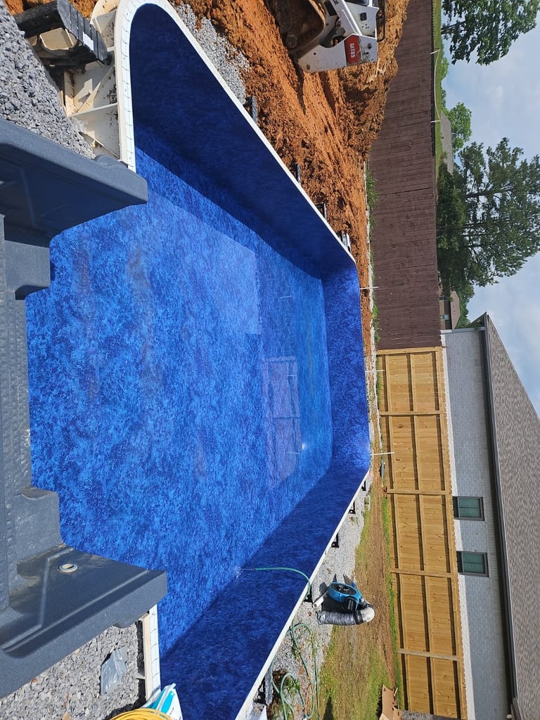 Aerial view of a bright blue swimming pool in a residential backyard surrounded by brick walls and wooden fence