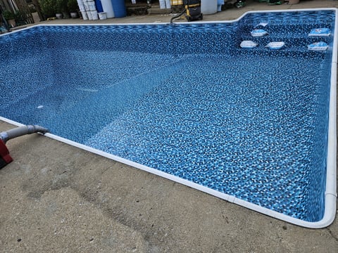 Rectangular swimming pool with blue tile interior and white edge